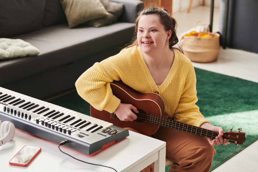 Modern young woman with Down syndrome spending time at home enjoying playing guitar